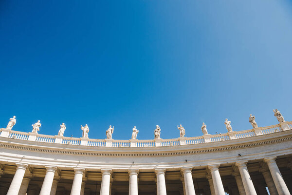 bottom view of statues at St Peters Square on blue sky in Vatican, Italy