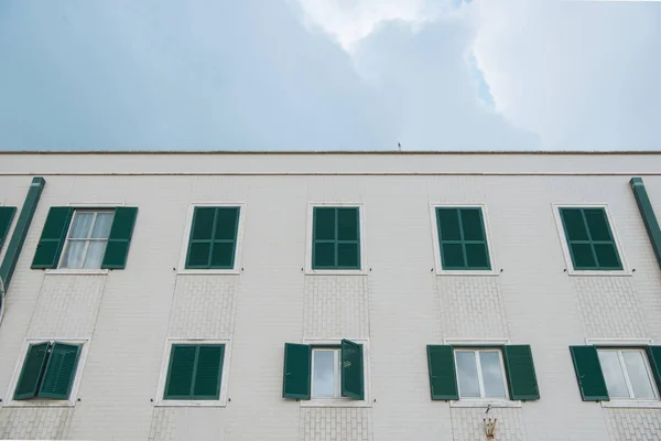Vista inferior del edificio europeo con ventanas cerradas frente al cielo nublado, Anzio, Italia - foto de stock