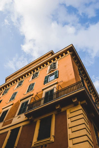 Blick von unten auf orangefarbenes Gebäude und bewölkten Himmel in Rom, Italien — Stockfoto