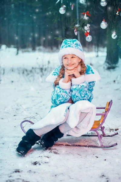 Neujahr. Kleines Mädchen rodelt zu Weihnachten im Wald — Stockfoto