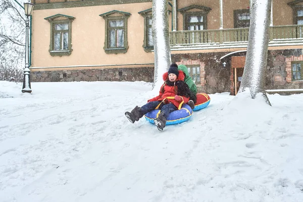 Malý chlapec sáňkaří v zimě. dítě sklouzne z hory na trubce — Stock fotografie