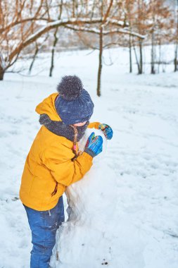 Küçük kız kışın bir kardan adam heykeli yapıyor.