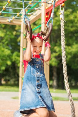 Parkta oynayan küçük bir kız. Çocuk jimnastik yüzüklerinde sallanıyordu.