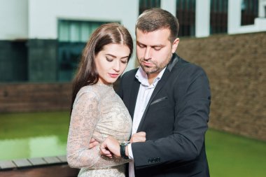 Erkek ve kadın kucaklaşıyor. Erkek ve kız saate bakıyorlar.