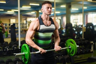 Genç adam halteri pazılar için kaldırıyor. Spor salonunda kaslı adam eğitimi. vücut geliştirme