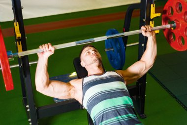 Genç adam halteri pazılar için kaldırıyor. Spor salonunda kaslı adam eğitimi. vücut geliştirme