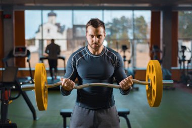 Sporcu çocuk halterle antrenman yapıyor. Spor salonunda ağırlık yapan atletik bir adam.