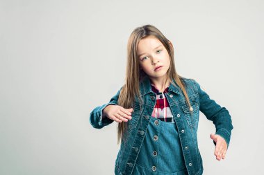 Küçük kız bir robot tasvir ediyor. Çocuk stüdyoda poz veriyor ve elleriyle ve ayaklarıyla hareket ediyor. Çocuk modası