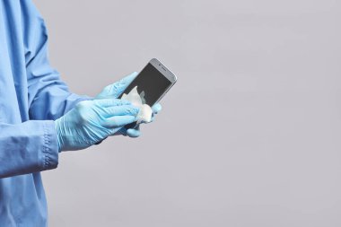 Telefonun dezenfektanla dezenfekte edilmesi. Doktor akıllı telefonu dezenfekte eder ve peçeteyle siler. Boşluğu kopyala