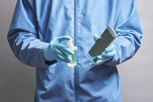 Telefonun dezenfektanla dezenfekte edilmesi. Doktor akıllı telefonu peçeteyle dezenfekte eder ve siler.