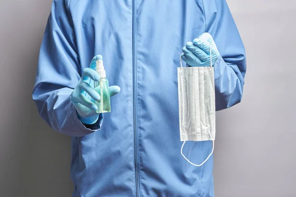 doctor holds a medical mask and a sanitizer