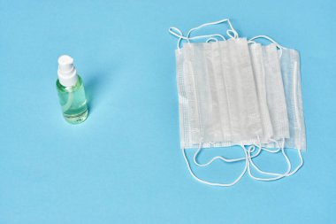 Mavi arka planda beyaz tıbbi maske ve antiseptik.