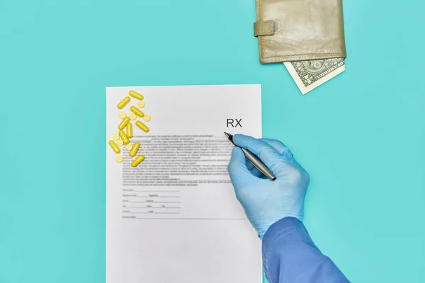 Eldivenli doktor haplara RX reçetesi yazıyor. Üzerinde bir dolar olan bir cüzdan var. Sağlık ve tedavi maliyetleri kavramı