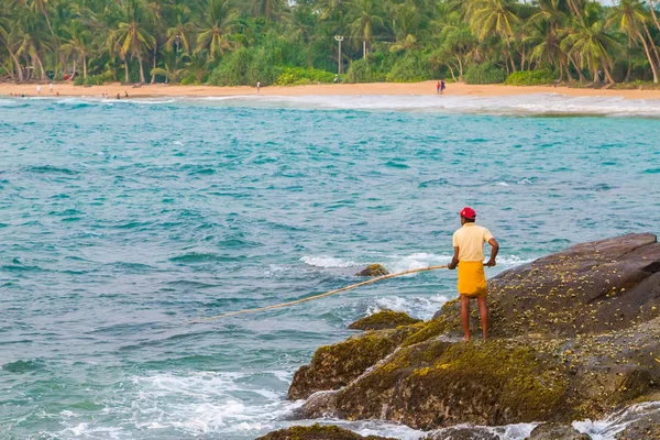 Pescador captura peces en una playa tropical — Foto de Stock