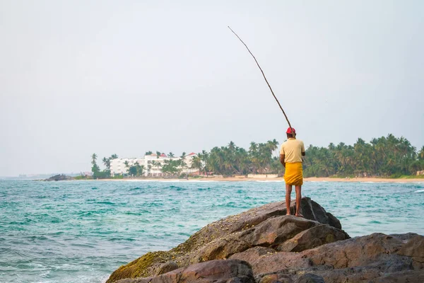 Fisherman catches fish on a tropical beach — Stock Photo, Image