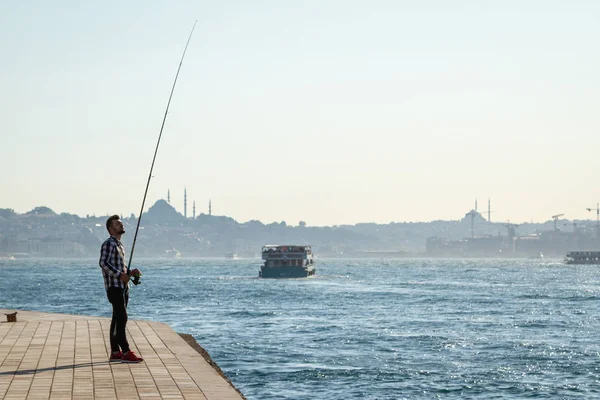 İstanbul, Türkiye. İnsan arka planda denizde balık yakalar. 