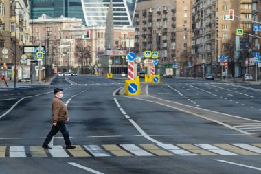 Covid-19, Moskova 'da karantina, Rusya' da koronavirüs. İnsanlar olmadan sokaklar bomboş. Koruyucu tıbbi maskeli adam karşıdan karşıya geçiyor..
