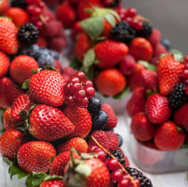 Bayas en cestas de plástico. Fresas frescas, frambuesas, bla —  Fotos de Stock