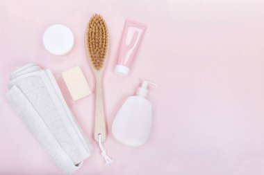Spa products: soap,body brush,body cream, linen towel over pink background 