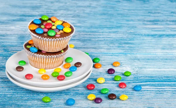 Muffins Mit Schokolade Und Farbigen Tropfen Über Blauem Holzhintergrund — Stockfoto