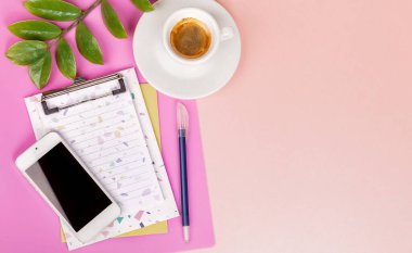 Planlayıcı, kalem, akıllı telefon, bir fincan espresso, yeşil dal, pembe arka grup.