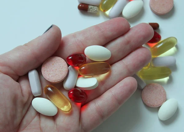 Various pills and medicines in a woman's hand