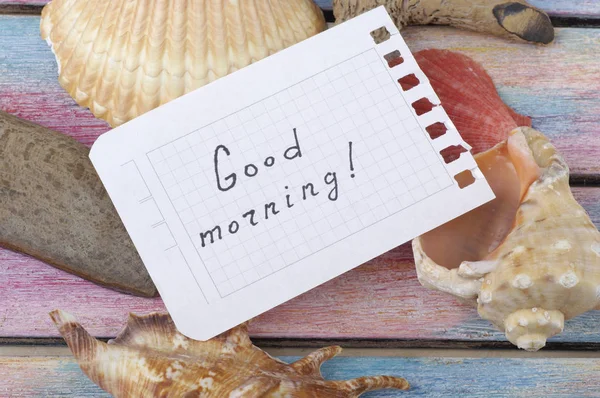 Inscripción Buenos días en un escritorio con conchas marinas — Foto de Stock