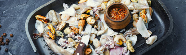 Сырые морепродукты со свежими мидиями, моллюсками, кальмарами, креветками в гриле pan.Long баннер
