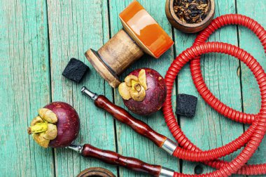 Mangosteen aromalı shisha tütünlü Asyalı nargilesi. Ahşap arka planda meyve nargile tütünü.