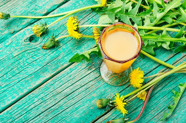 Homemade spring wine from dandelion flowers on old wooden table