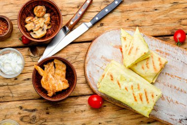 Geleneksel doğu shawarması. Mutfak tahtasında tavuk, peynir ve mantar var.