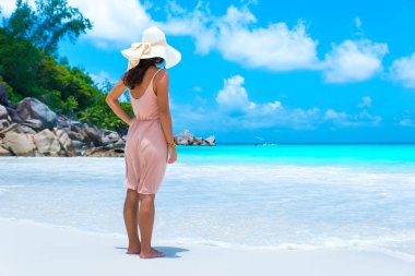 Anse Georgette Praslin, Seyşel Adaları, sahilde duran genç kadın yan görünüm.