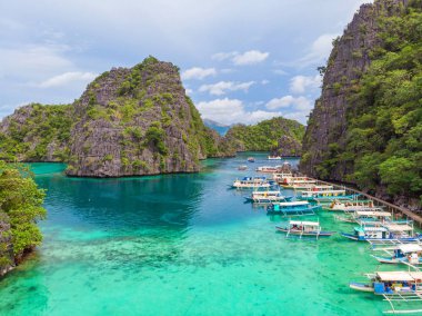 Filipinler, Palawan 'daki Coron Adası' ndaki Kayangan Gölü 'ndeki ahşap iskelede tekneleri olan Cennet Koyu' nda mavi kristal su..