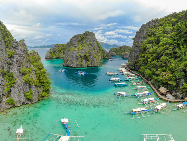 Blue crystal water in paradise Bay with boats on the wooden pier at Kayangan Lake in Coron island, Palawan, Philippines.