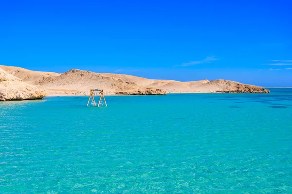 Orange Bay Beach with crystal clear azure water and white beach -  hammock in the water for relaxing - paradise coastline of Giftun island, Mahmya, Hurghada, Red Sea, Egypt.