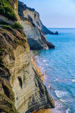 Peroulades 'teki Loggas plajı, Korfu' da, İyon adası, Yunanistan ve Avrupa 'nın yakınlarındaki yüksek kayalık beyaz kayalık ve kristal berrak gök mavisi suyu olan bir cennet kumsalı.