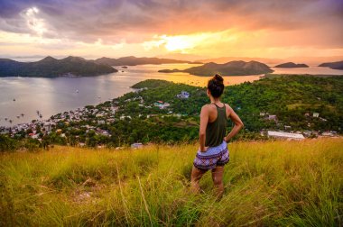 Gün batımında Busuanga Adası 'ndaki Tapyas Dağı' ndan Coron Town ve Bay 'e bakan kız. Cennet manzaralı tropikal bir yer, Palawan, Filipinler..