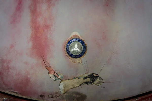 Hood emblem of Mercedes-Benz on a rusty body. — Stock Photo, Image