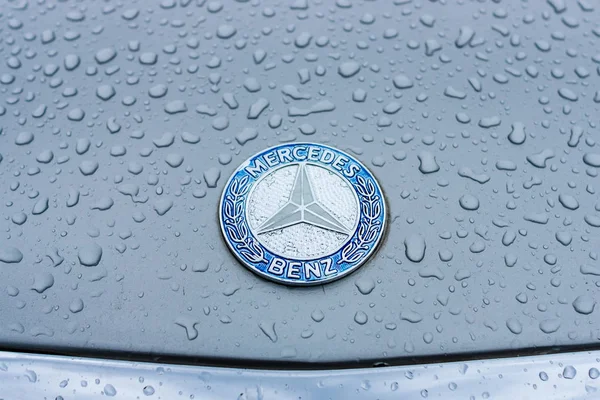Znak na kapotě Mercedes-Benz v dešťové kapky na šedém pozadí. — Stock fotografie