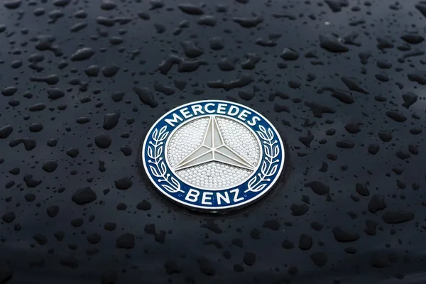 Capuz emblema de Mercedes-Benz em gotas de chuva no fundo escuro . — Fotografia de Stock