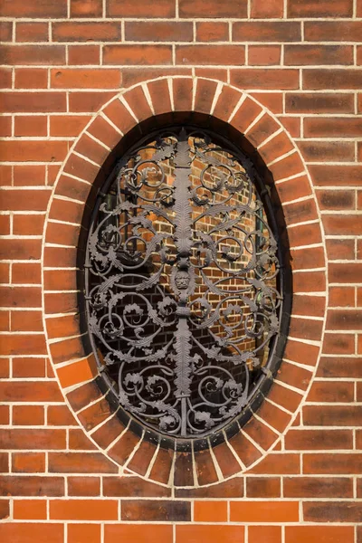 Кованая железная решетка с цветочными узорами на овальном окне . — стоковое фото