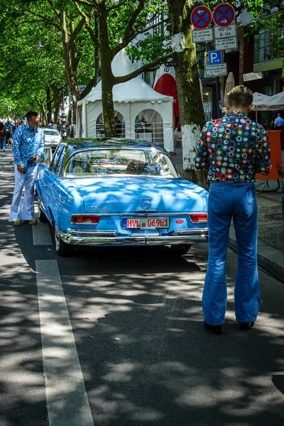 Deux hommes habillés dans le style des années 70 regardent Mercedes-Benz 220 SE . — Photo
