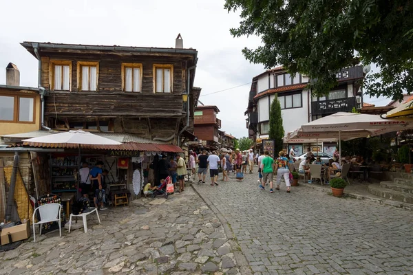 A typical residential building and a street with tourists in the old town. Nesebar is an ancient city and one of the major seaside resorts on the Bulgarian Black Sea Coast. — Stock Photo, Image