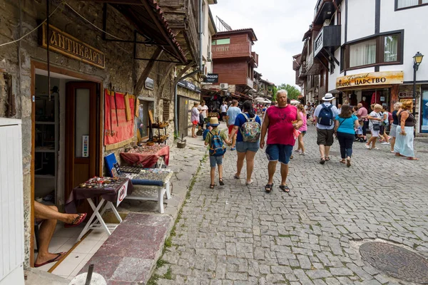Typický bytový dům a ulice s turisty na starém městě. Nesebar je starobylé město a jedno z hlavních přímořských letovisek na bulharském pobřeží Černého moře. — Stock fotografie