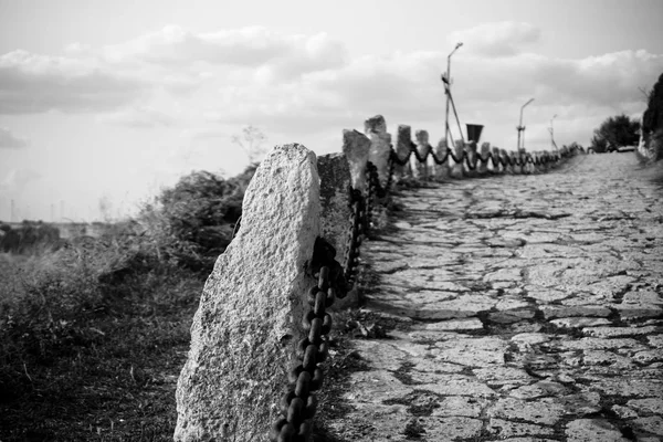 La vecchia strada di pietra che parte in lontananza. Bianco e nero . — Foto Stock
