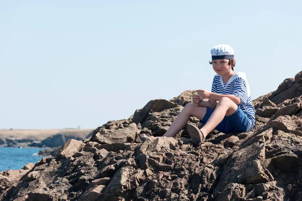 Poika Raidallisessa Paidassa Lakissa Istuu Kallioilla — kuvapankkivalokuva