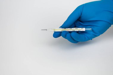 Tıbbi eldivenli doktor termometre tutuyor. Bir termometreyle. Tıbbi eldivenler.