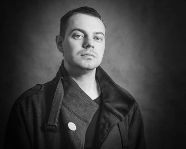 Siyah arka planda ceketli genç bir adam..