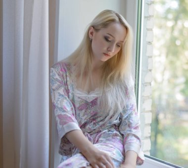 Pencerenin kenarında oturan kadın.