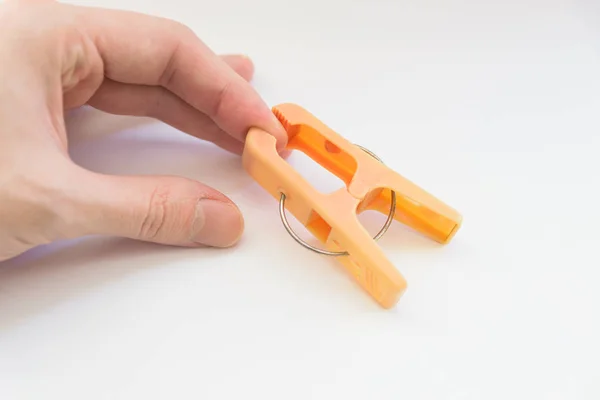 Pomarańczowy Clothespin Pinch Rękę Białym Tle — Zdjęcie stockowe